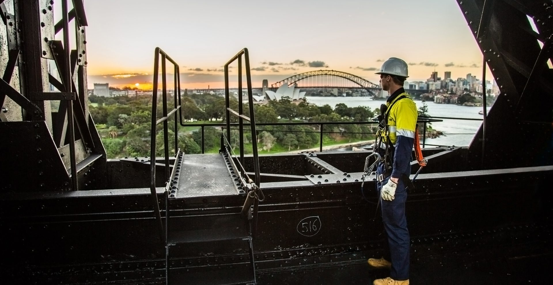 Staff dressed in full safety gear viewing the Sydney Harbour Bridge on the top of a demolition site